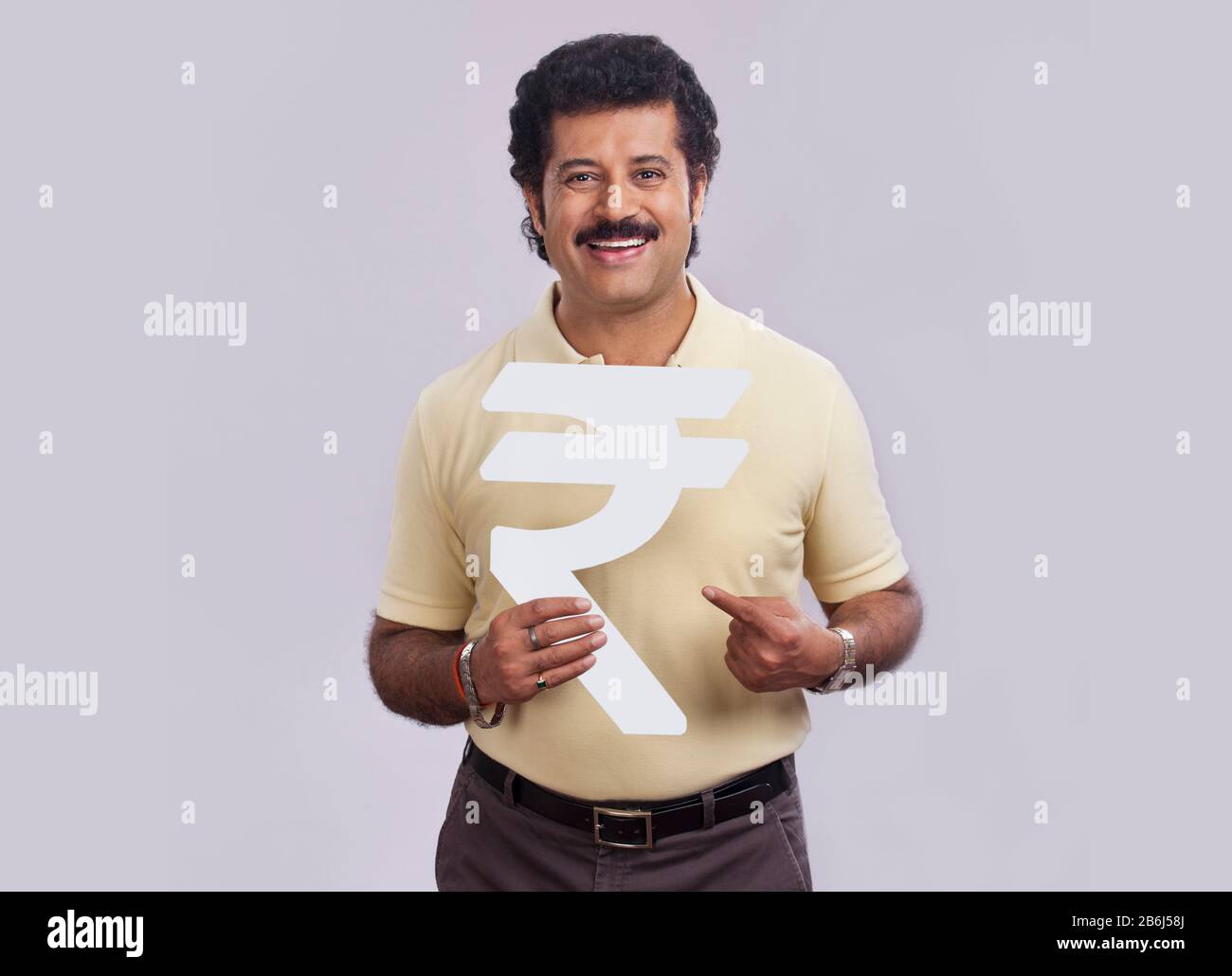 Homme de bonne humeur pointant vers un symbole de roupie en carton. Banque D'Images