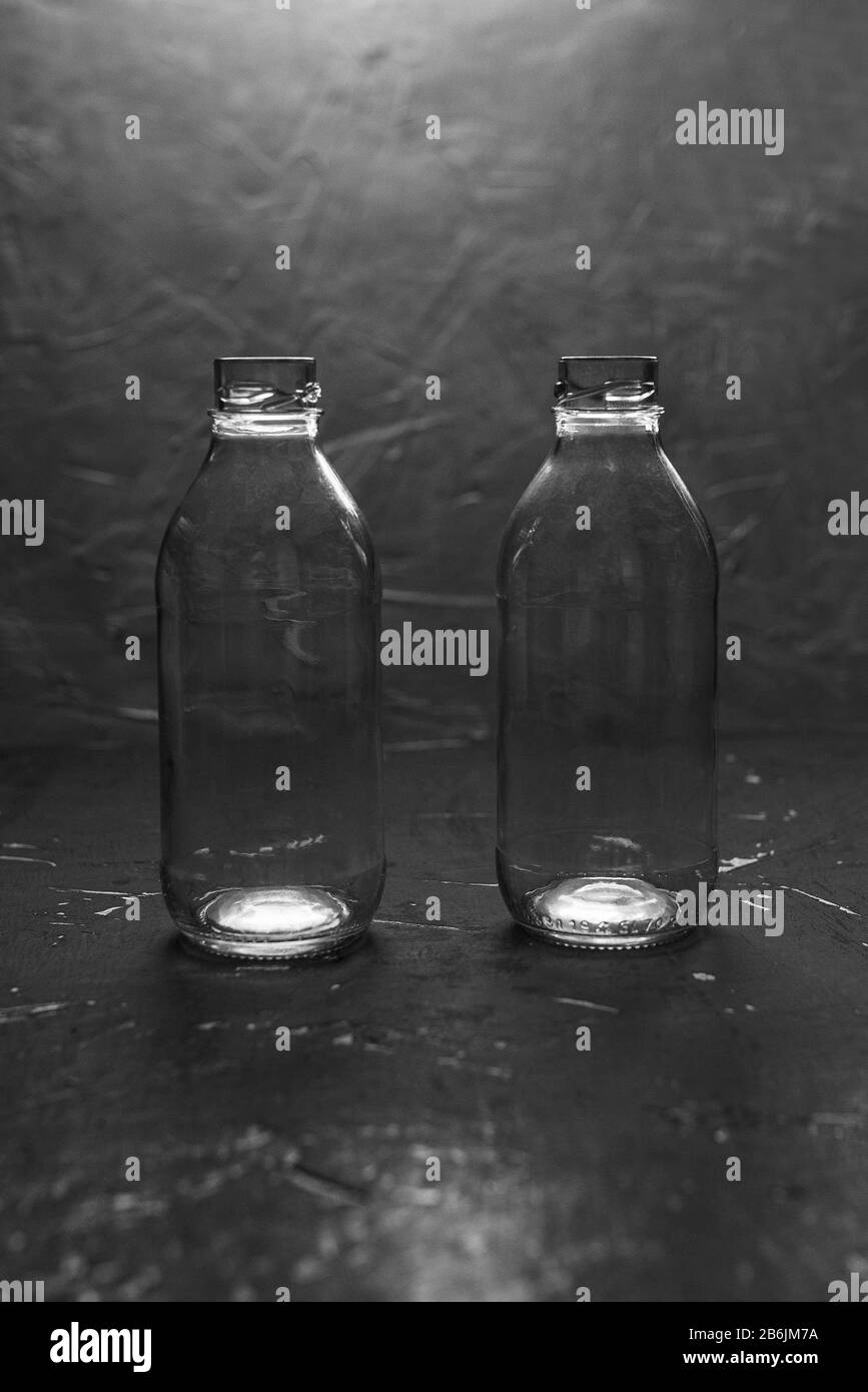 Deux petites bouteilles en verre vides sur fond noir. Le Minimalisme Banque D'Images