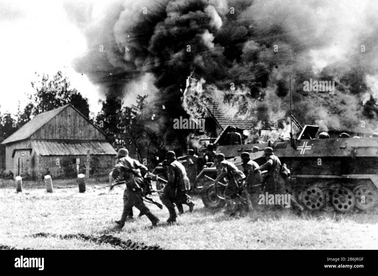Les soldats allemands DU FRONT oriental traversent un village russe en feu en 1941, soutenu par un transporteur de troupes blindé Banque D'Images