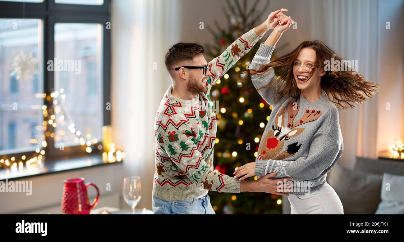 Célébration, de plaisir et de vacances concept - heureux couple portant des chandails laids dancing au party de Noël Banque D'Images