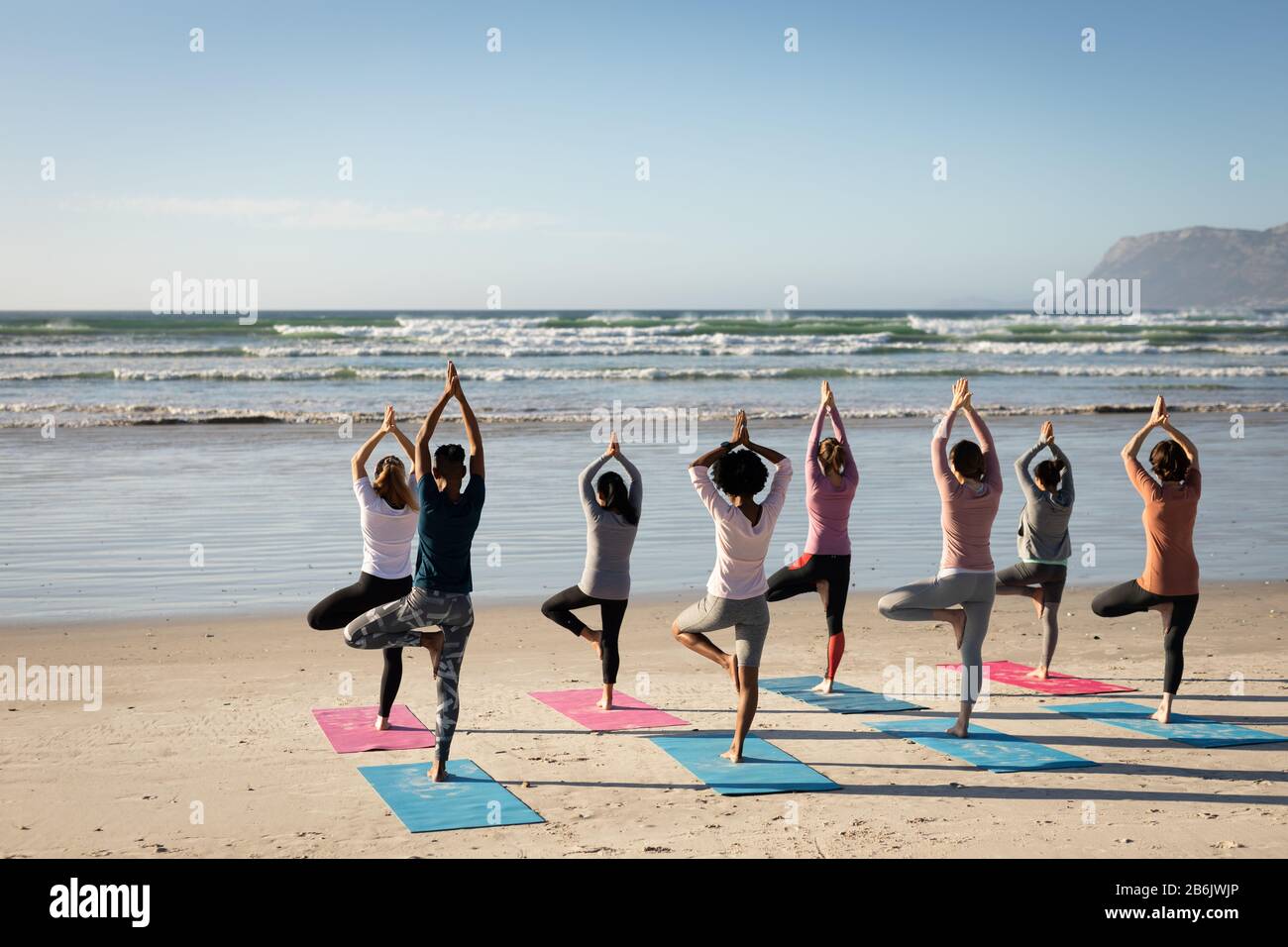 Vue arrière des femmes faisant du yoga ensemble à la plage Banque D'Images