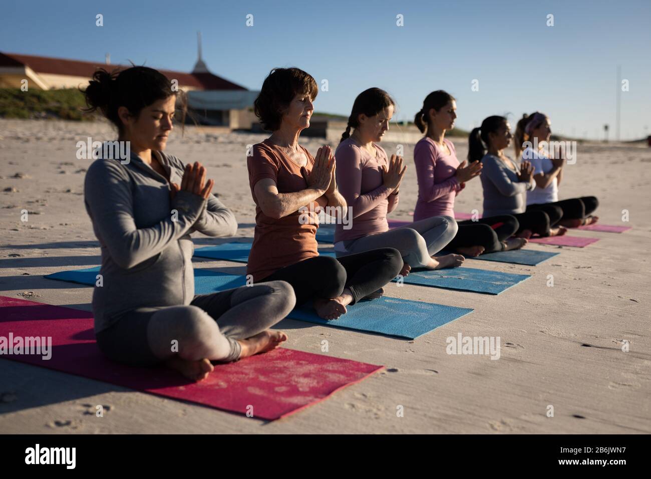 Vue latérale des femmes faisant du yoga à la plage Banque D'Images