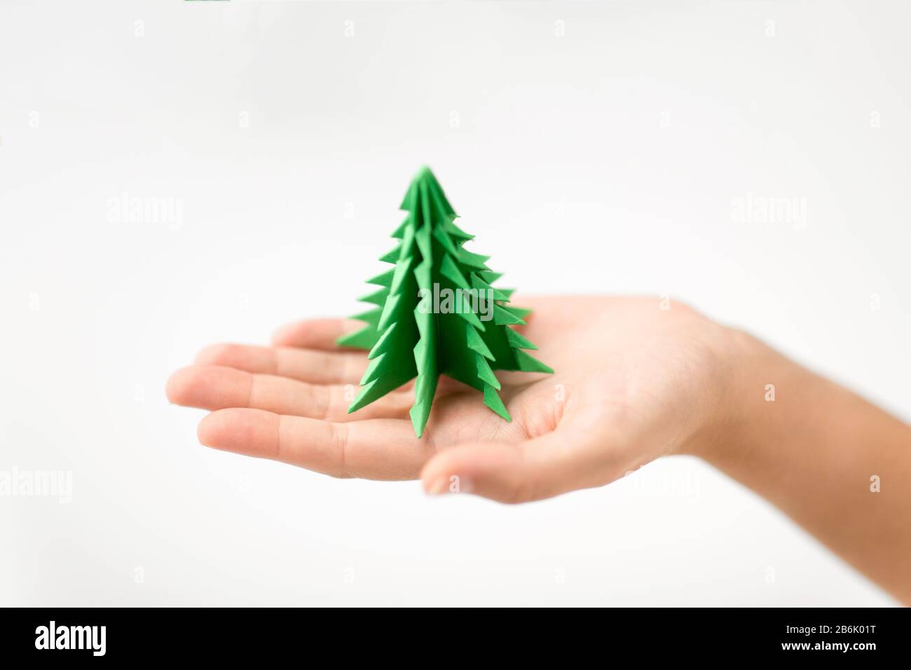 vacances d'hiver, nouvelle année et concept d'artisanat - main tenant le papier vert origami arbre de noël Banque D'Images