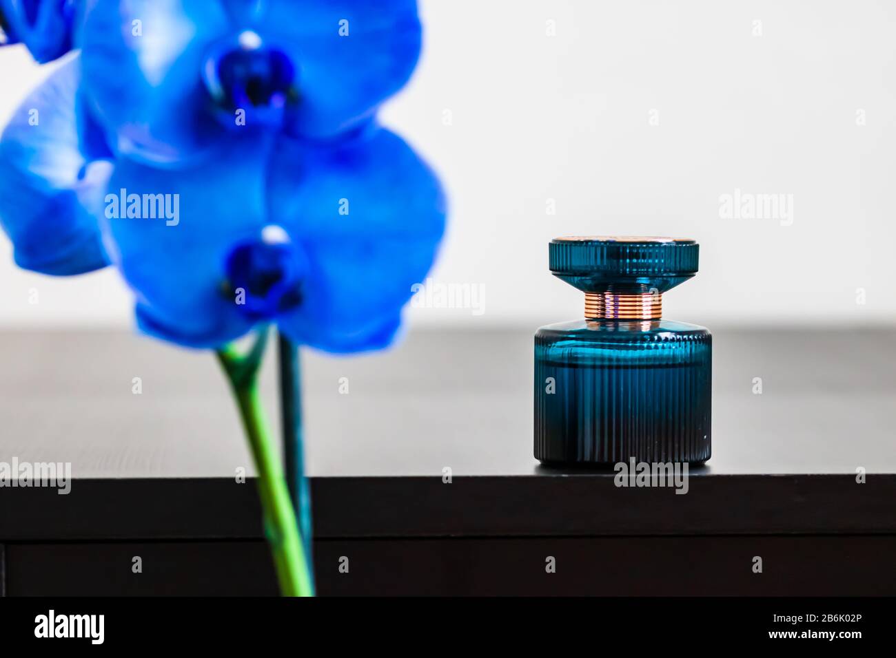 Orchidée bleue floue en premier plan avec bouteille de parfum en arrière-plan. Banque D'Images