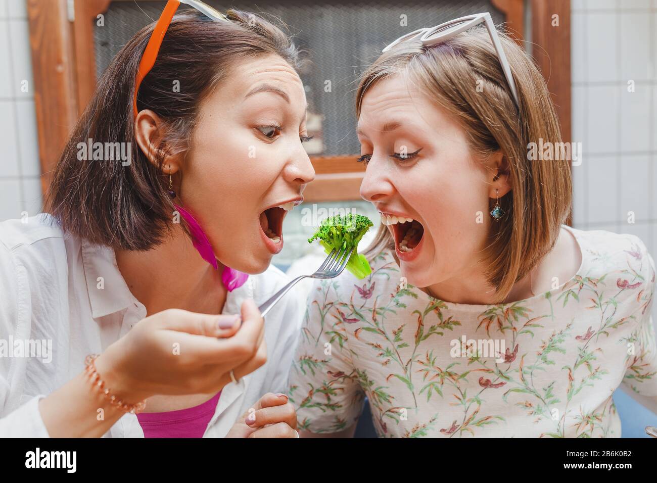 portrait de deux filles amis mangeant le brocoli avec une fourchette Banque D'Images