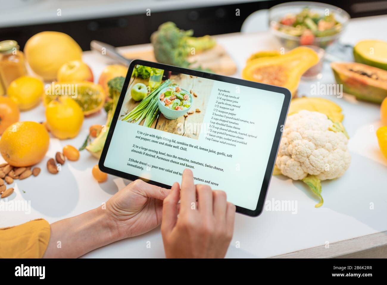 Femme regardant la recette numérique, en utilisant une tablette tactile pendant la cuisson de repas sains dans la cuisine à la maison, vue rapprochée sur l'écran Banque D'Images