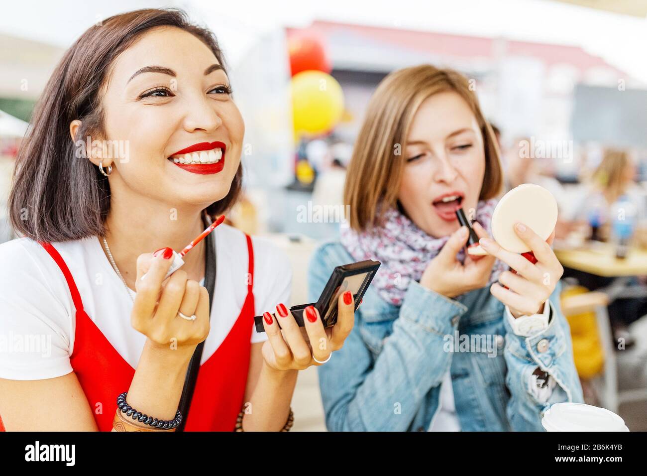 Deux filles petite amie mettre sur le maquillage, rouge à lèvres et regarder dans le miroir. Le concept de cosmétiques et de relations de style de vie Banque D'Images