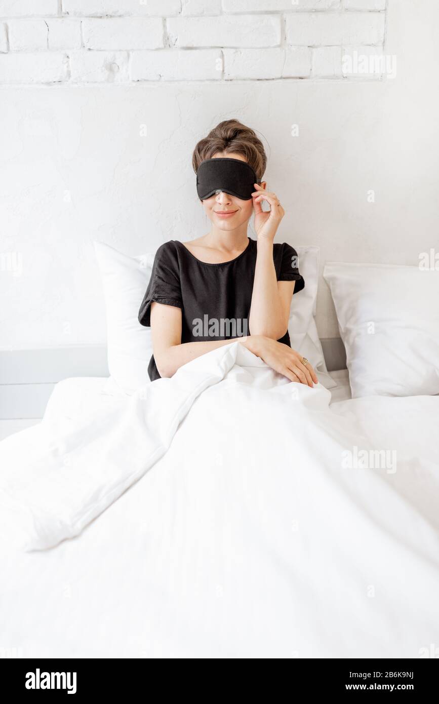 Jeune femme dans le masque de sommeil se réveillant dans la chambre. Concept de Bonjour Banque D'Images