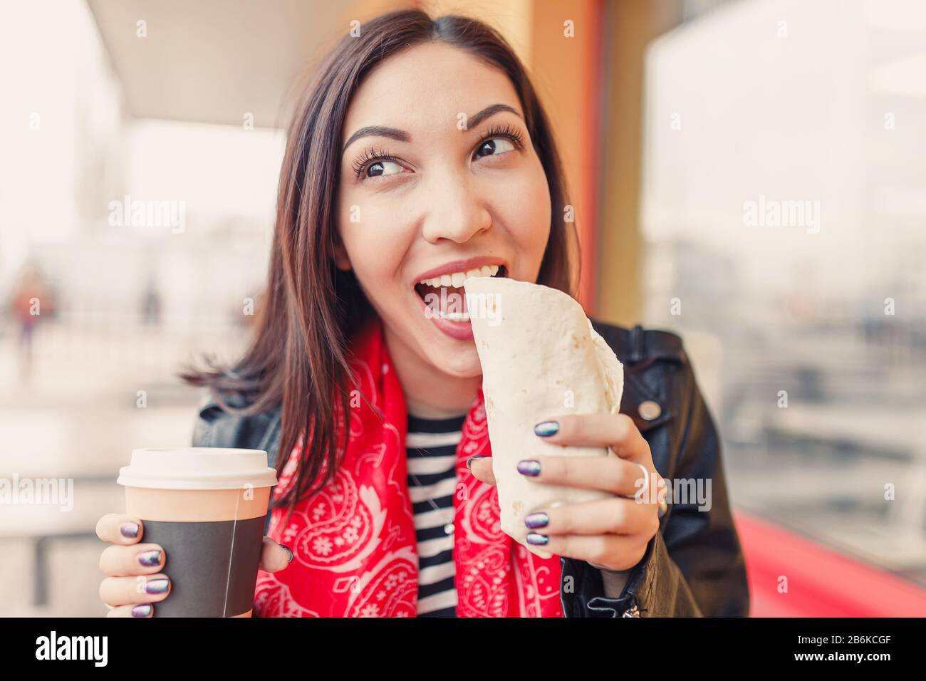 portrait d'une jolie femme qui boit une tasse de café et manger des en-cas dans un café de restauration rapide Banque D'Images