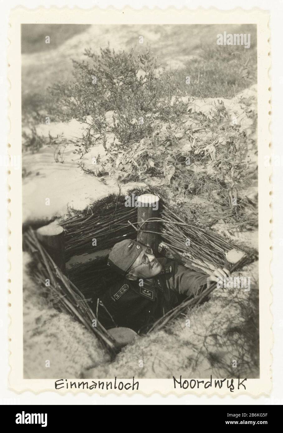 Soldat allemand à Einmannloch un soldat allemand regarde d'un Ëinmannloch (foxhole) dans les dunes près de Noordwijk en hiver, il y a des énuuw. Fabricant : Photographe : fabrication anonyme Noordwijk Date: Mai 1940 - 1943 Caractéristiques physiques: Gélatine argent imprimé matériel: Papier technique: Gélatine argent imprimé dimensions: H 9 cm. B × 6 cm. Note Le Même soldat avec des lunettes que sur les ennemis précédents. Objet: Profession  oorlogticatifetificationsTweede II Occupation des Pays-Bas Quand: 1940 - 1943 Banque D'Images