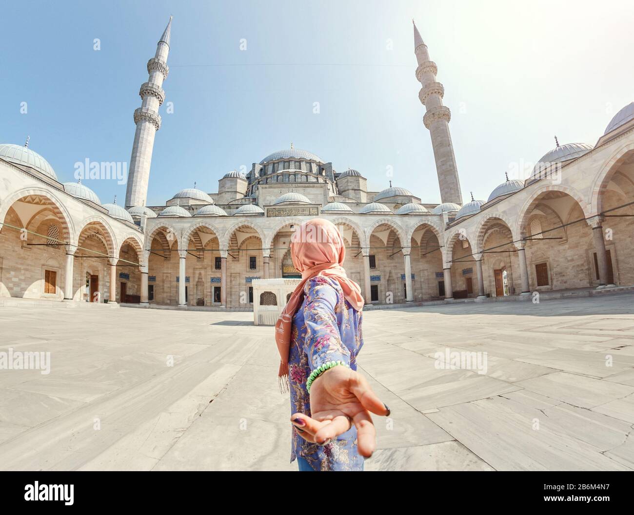 Suivez-moi. Une femme musulmane dans un foulard conduit son ami à la mosquée turque Suleymaniye, voyage et concept de religion. Banque D'Images