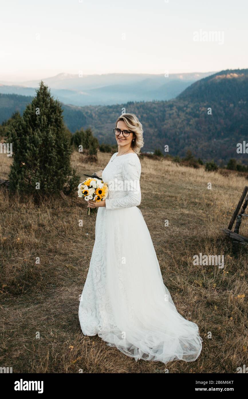 Portrait de La Belle mariée élégante en dentelle robe de mariage avec longue jupe complète et manches longues. Jolie fille en blanc. Nature, avec ville dans le backgr Banque D'Images