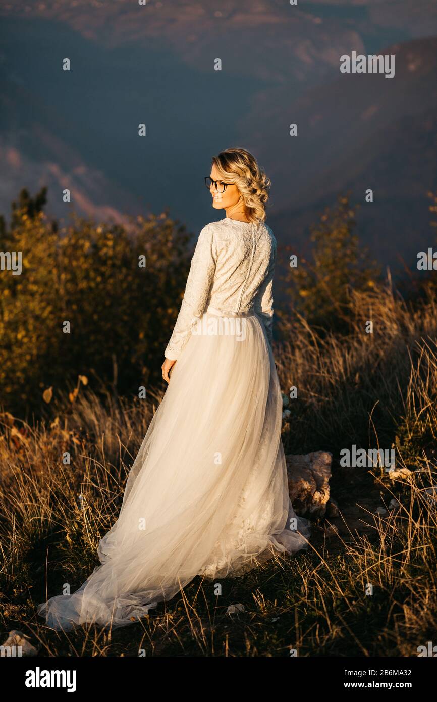 Portrait de La Belle mariée élégante en dentelle robe de mariage avec longue jupe complète et manches longues. Jolie fille en blanc. Nature, avec ville dans le backgr Banque D'Images