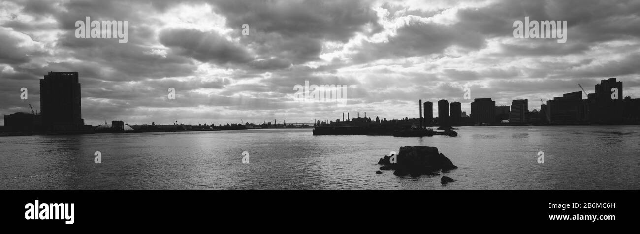 Silhouette de bâtiments des deux côtés d'une rivière, Queens et Lower Manhattan, East River, New York City, New York State, États-Unis Banque D'Images