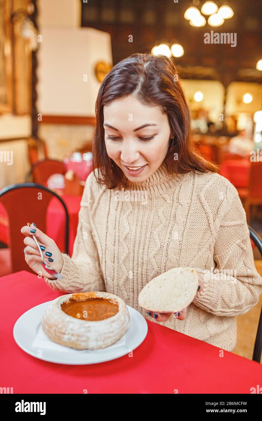 Femme mangeant une célèbre soupe traditionnelle hongroise et polonaise - goulash de boeuf servi dans un bol à pain Banque D'Images