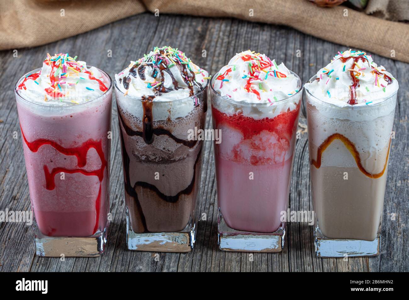 Quatre verres de cocktails colorés à base de milk-shake au chocolat,  Milkshake aux fraises, Milkshake au caramel, Milkshake décoré de baies  fraîches Photo Stock - Alamy