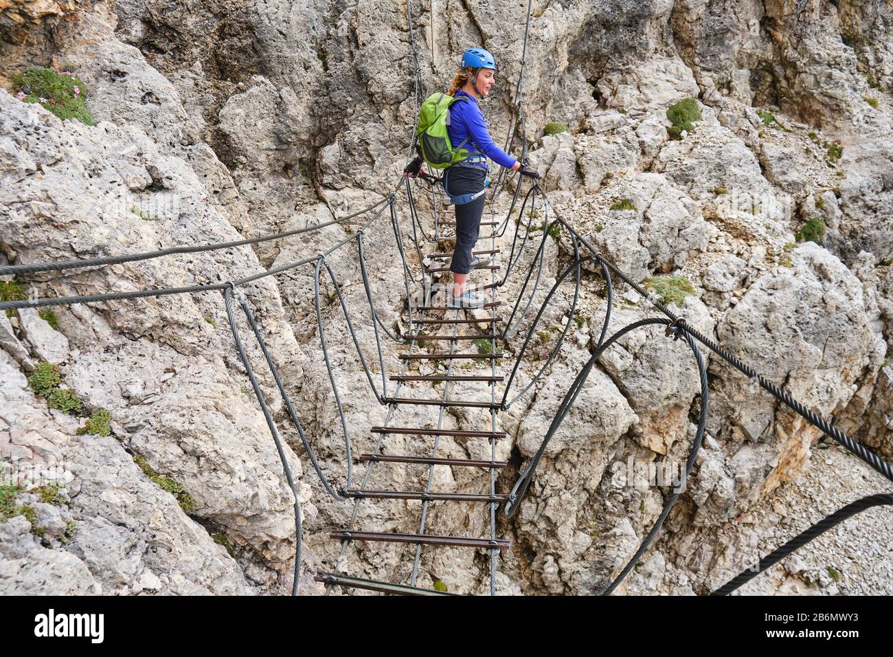 Femme sur un pont suspendu via ferrata à Cesare Piazzetta klettersteig route, groupe Sella, Dolomites montagnes, Italie. Banque D'Images