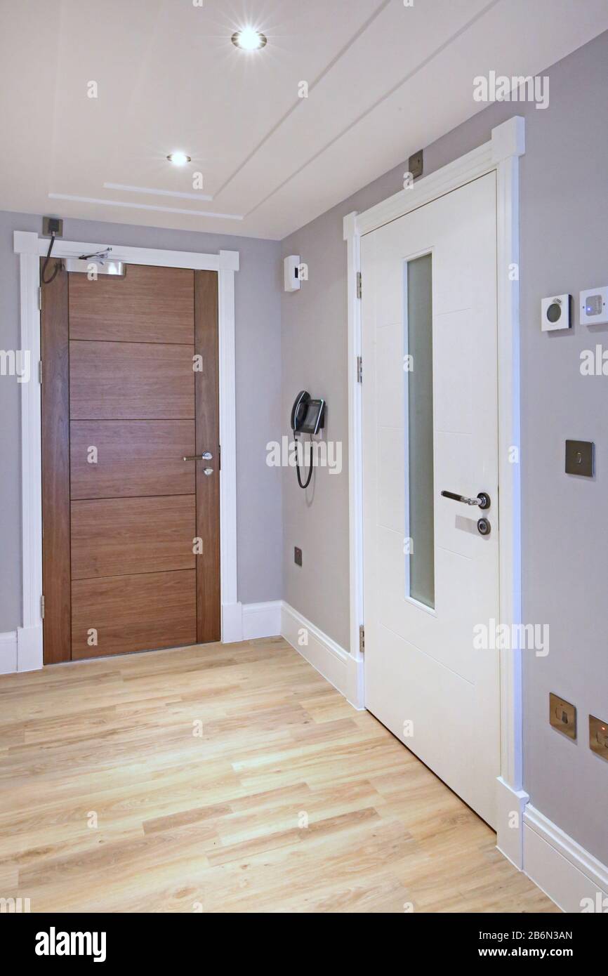 Hall d'entrée dans un nouvel immeuble de Londres montrant une porte de feu de bois franc avec ferme-porte automatique, téléphone principal, thermostat et porte de feu interne Banque D'Images