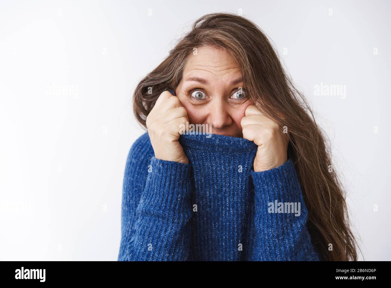 Granny jouant peekaboo avec les enfants. Portrait d'une femme d'âge moyen amusante et ludique, épétée, avec des rides qui se cachent dans le col du pull tirant sur le visage Banque D'Images