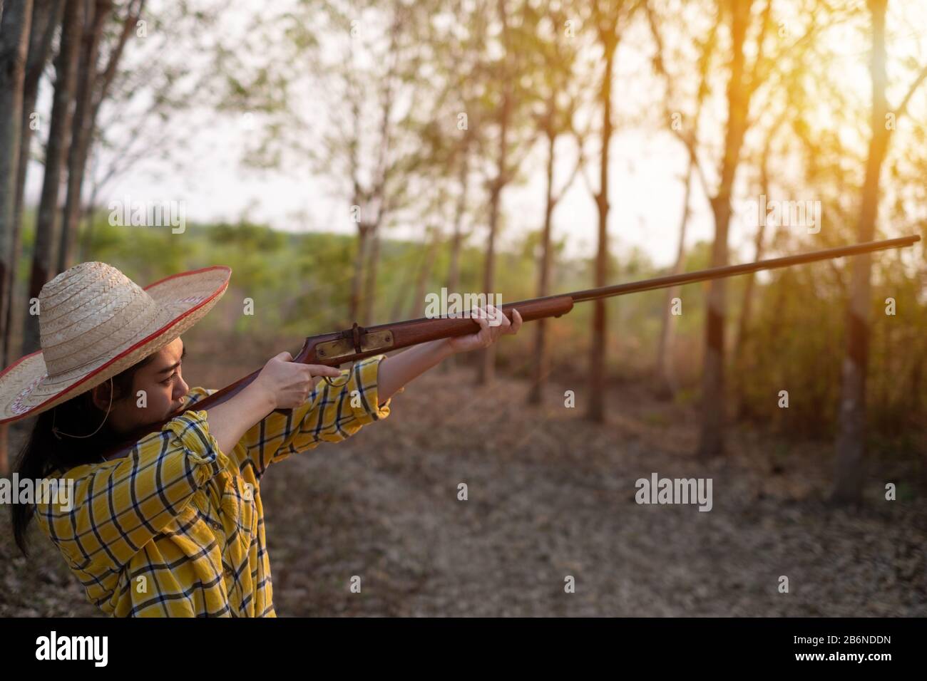 Portrait l'agriculteur asea femme portant un chapeau à l'aire de tir tourné à partir d'un fusil d'époque à chargement museau dans la ferme, jeune fille debout dans l'atti Banque D'Images