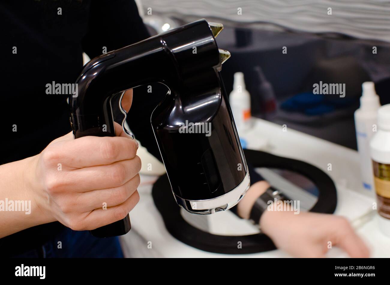 main d'esthéticienne tenant airbrush-pistolet pour le traitement de bronzage de pulvérisation dans un salon de beauté professionnel Banque D'Images