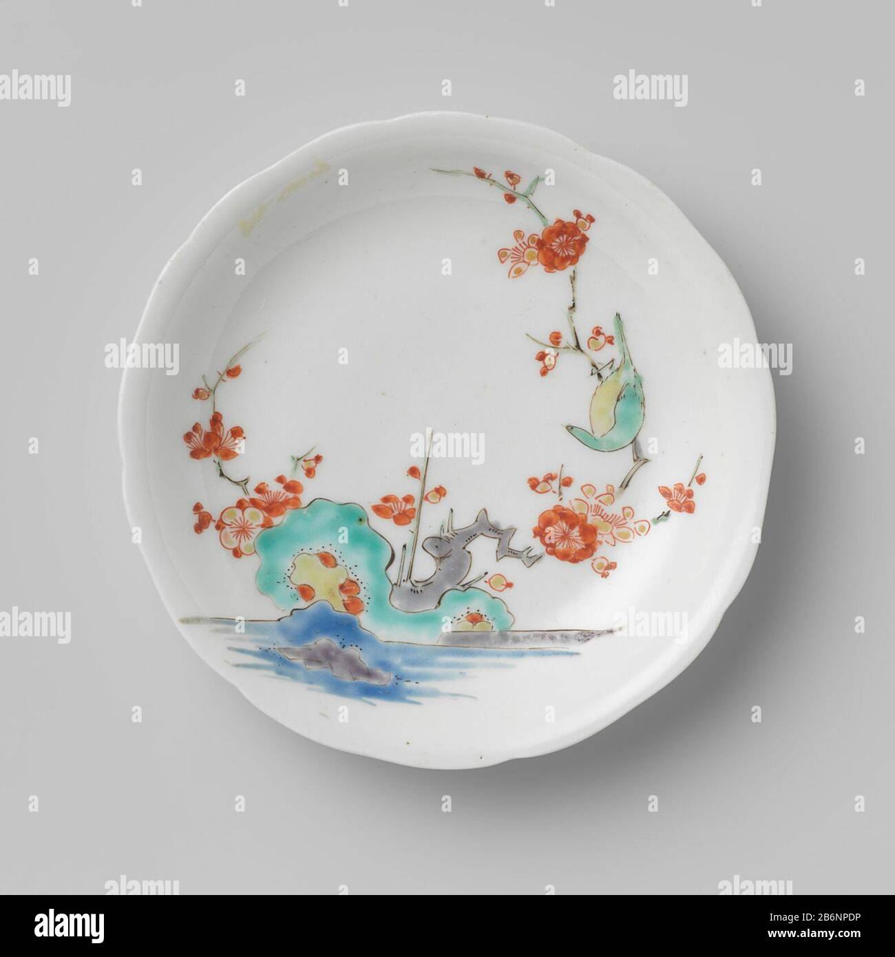 Gelobde schotel met bloemtak en vogel Gelobde schotel van porselein, beschilderd op het glaruur in blauw, rood, groen, geel, aubergine en zwart, met op de kop een vogel met chrysanttakken, op de schotel een vogel in een ustak birotsen eau. Kop hoort Banque D'Images