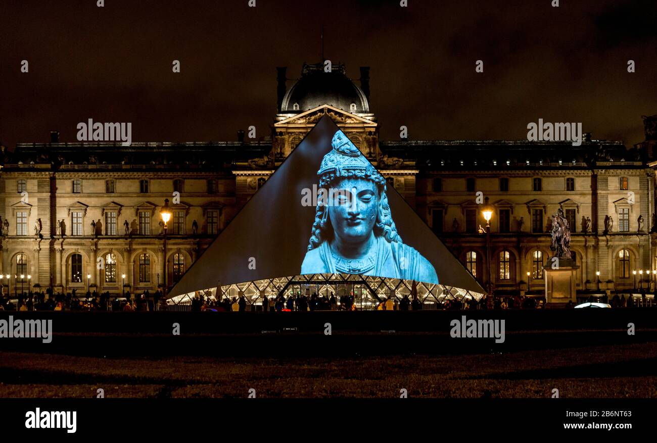 Expositions de la collection du Louvre affichées sur une entrée en pyramide de verre le soir, Paris, France Banque D'Images