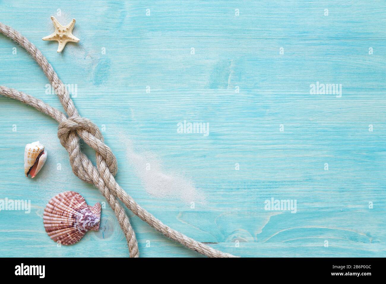 La corde de chanvre rugueuse liée au noeud marin, les coquillages et les étoiles de mer sont sur le fond de la terrasse en bois bleu délavé. Concept marin Banque D'Images