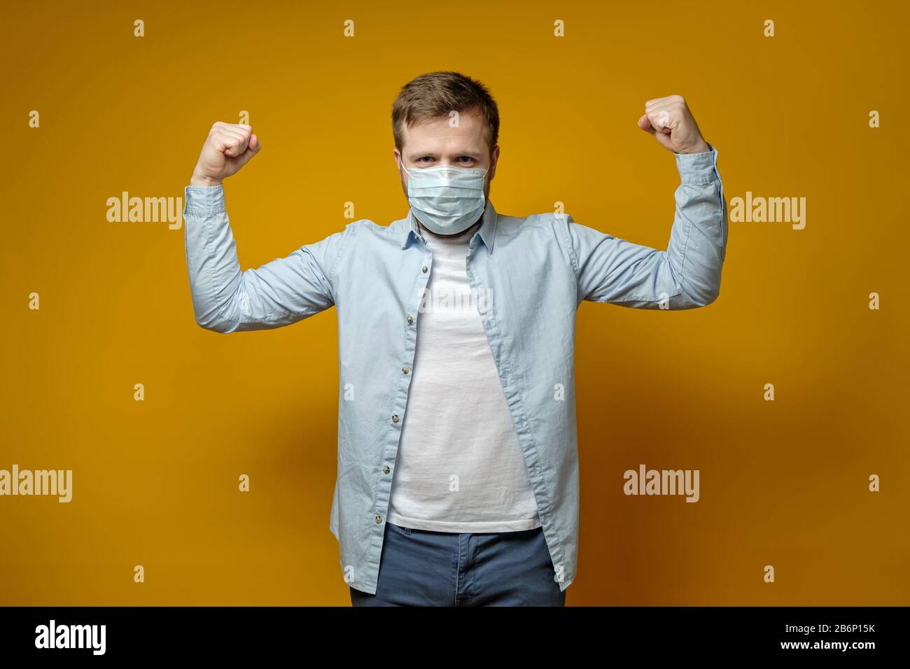 Homme satisfait mettre sur un masque médical sur le visage et se sent protégé des virus, montrant un geste de confiance avec les mains. Banque D'Images