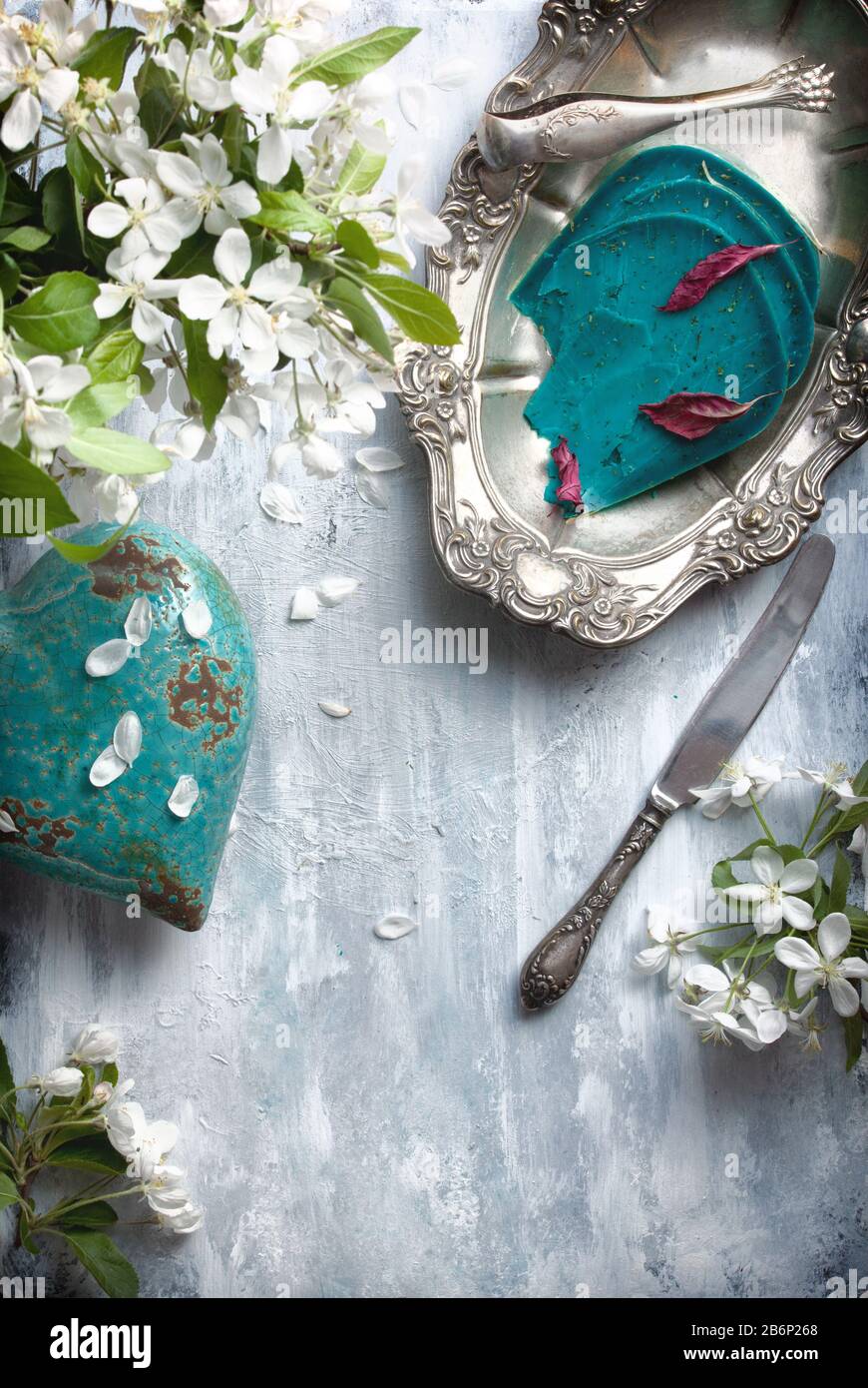 Flatlay - fond alimentaire vide table en bois avec des morceaux de fromage bleu, de fleurs blanches et de vaisselle antique argent Banque D'Images