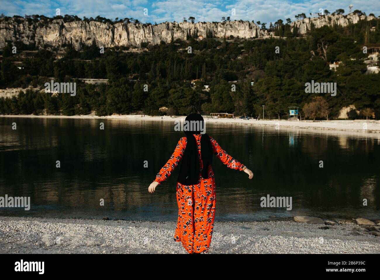 Portrait de jeunes femmes musulmanes européennes avec hijab assis sur la plage de pierre avec mer et port en arrière-plan. Elle est heureuse et détendue. Photo de Banque D'Images