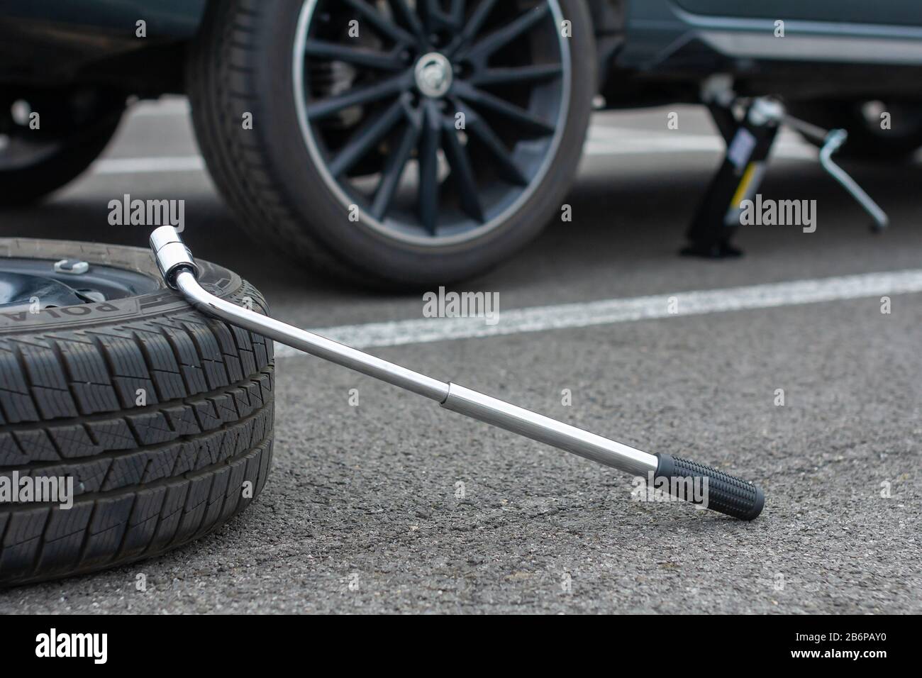 Une roue et un tournevis à pneu plat se trouvent sur une route asphaltée  sur le fond brisé de Skoda Rapid. Le cric soulève un véhicule. Service  automobile Photo Stock - Alamy