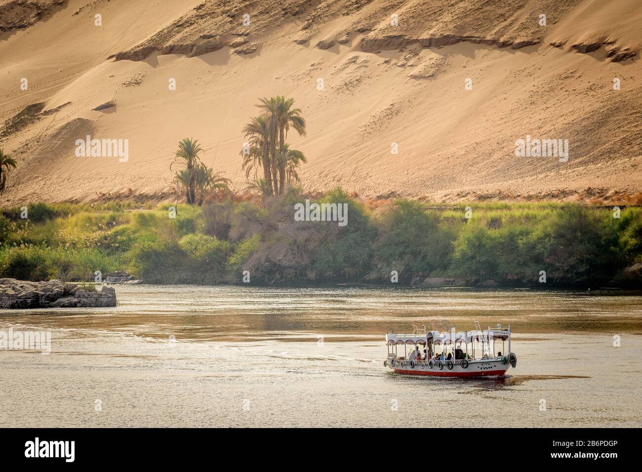 Un bateau naviguant dans le Nil en face des dunes de sable et des palmiers Banque D'Images