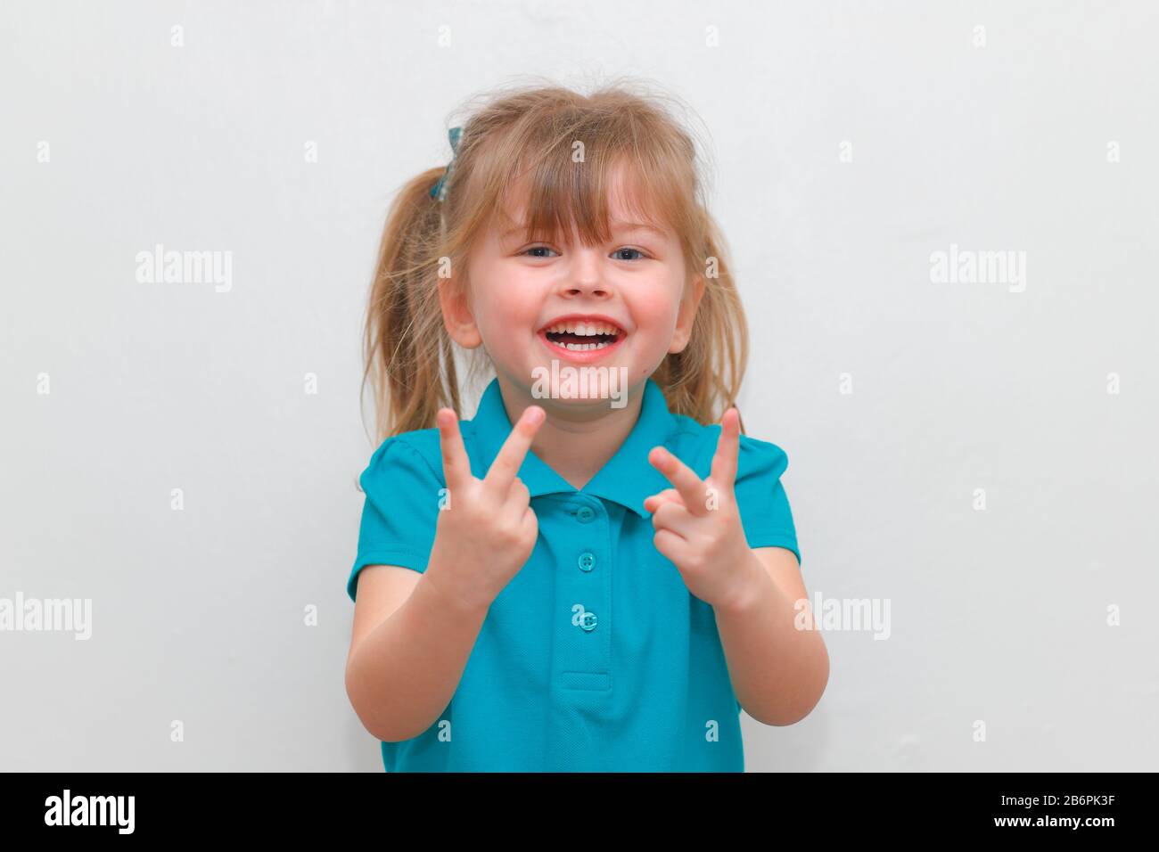Une petite fille qui se colle à 2 doigts vers le haut Photo Stock - Alamy