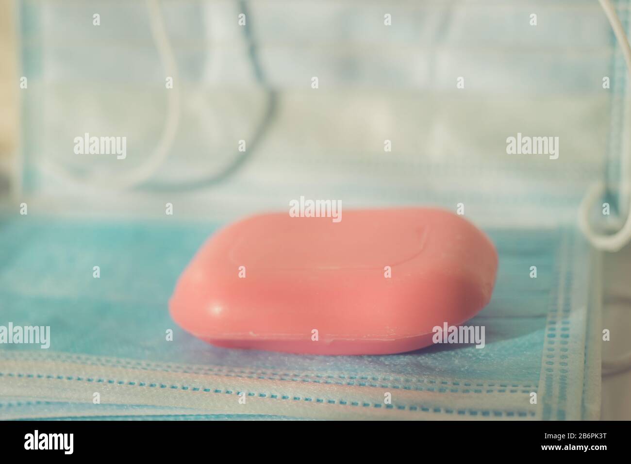 Une barre rose de savon sur les masques médicaux bleus dans la salle de bains. Banque D'Images