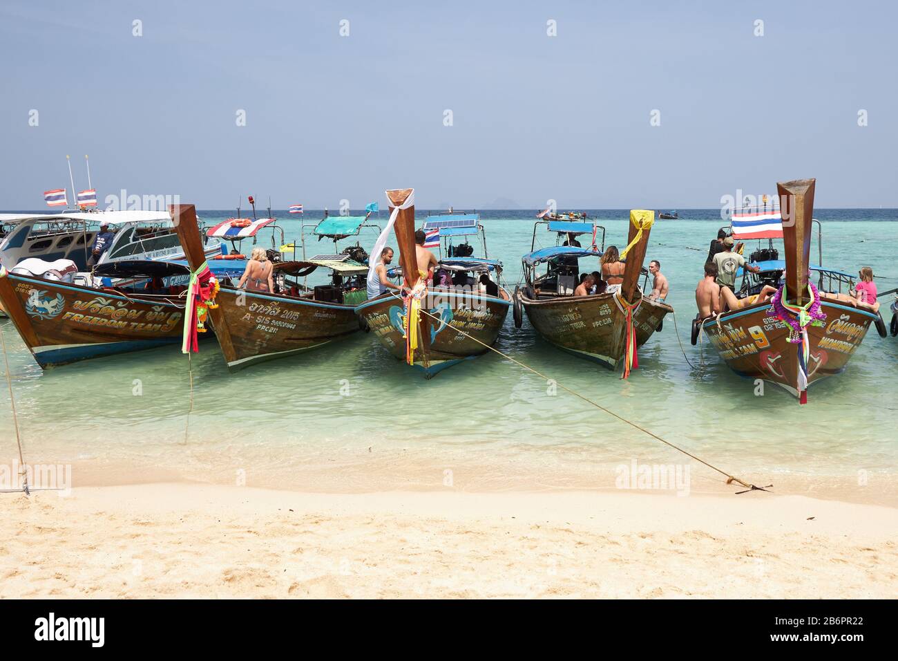 Phuket, Thaïlande, 04 février 2020: Plusieurs bateaux thaïlandais traditionnels avec des touristes se tiennent à la suite sur une magnifique plage sur une île près de Phuket Banque D'Images