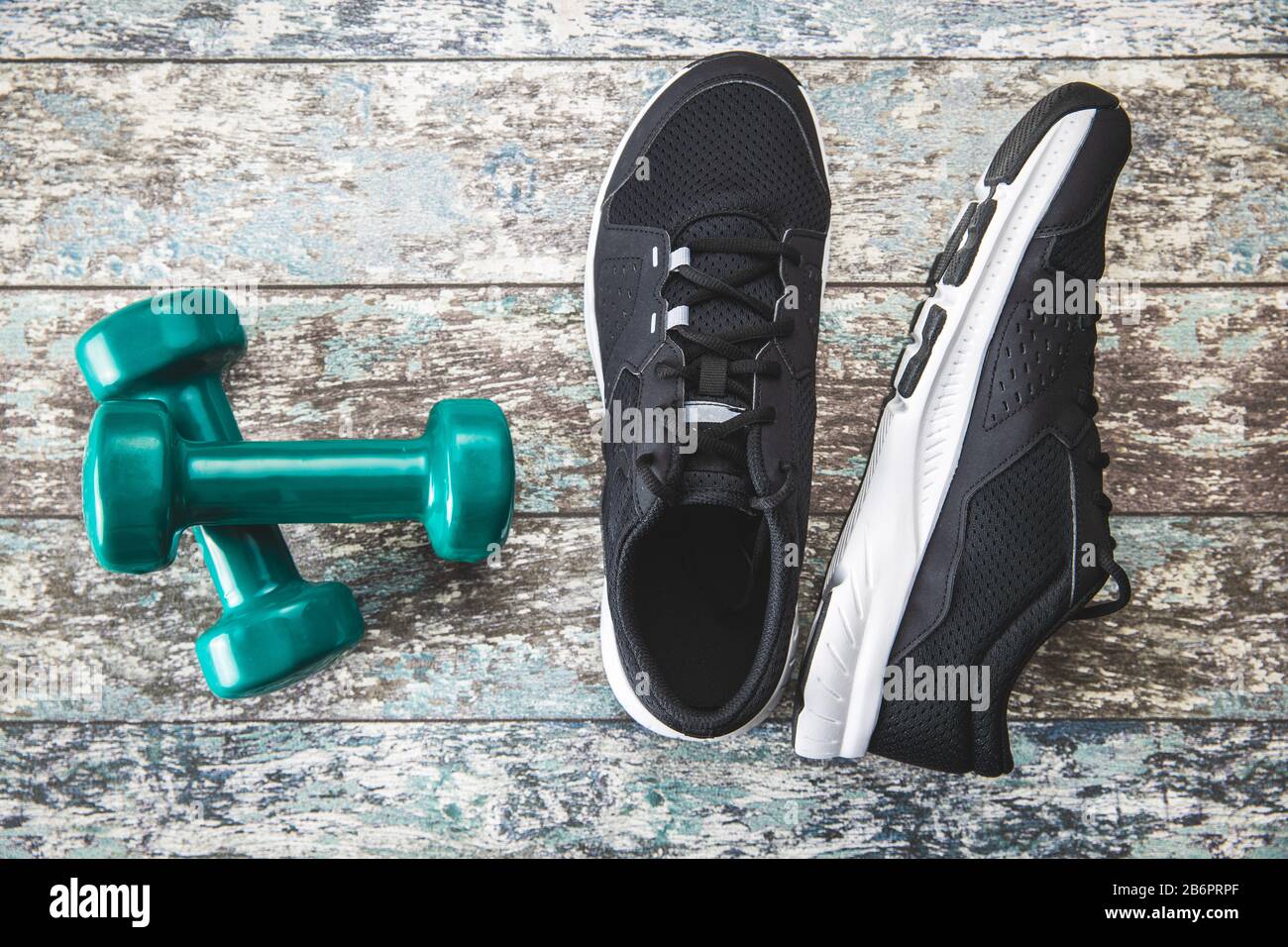 Chaussures de sport noires et haltères vertes sur fond rose. Vue de dessus. Banque D'Images