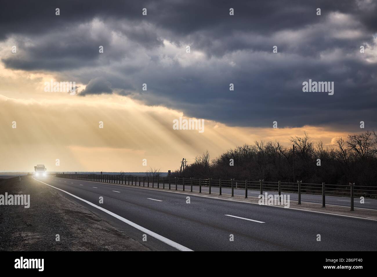 Le camion se déplace sur une route d'asphalte en arrière-plan des orages et des rayons du soleil. Banque D'Images