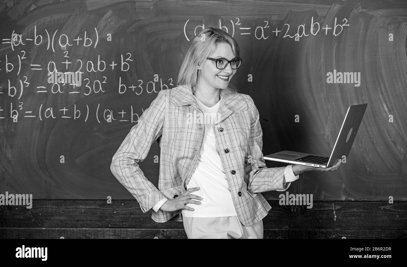 Concept de formation à distance. Enseignante portent des lunettes est titulaire d'ordinateur portable Internet surf. L'éducation scolaire de base. Dame élégante avec des enseignants pour ordinateur portable moderne tableau internet surf arrière-plan. Banque D'Images