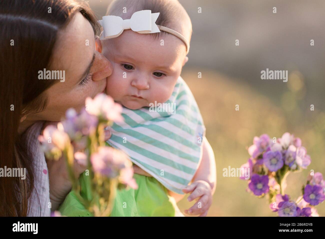 Une mère et son bébé s'arrêtent et sentent les fleurs. Banque D'Images