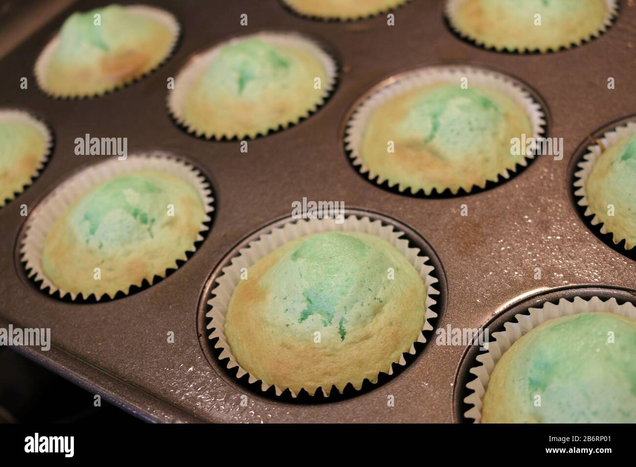 Cuisson des cupcakes verts pour la fête d'anniversaire dans un moule à muffins à colorier Banque D'Images