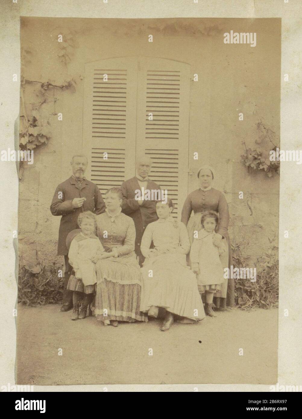 Groepsportret van twee mannen, drie vrouwen en twee kinderen staand voor een huis à Frankrijk partie de l'album du photographe amateur français avec des photos de famille, militaires, industriels, paysages, et un examen de où: Conditions à Frankrijk. Fabricant : Photographe: Fabrication anonyme: France Date: Mai 1883 matériau: Papier photo technique: Albumen formats d'impression: H 151 mm × W 107 mm Objet: Groupe familial, en particulier les parents garrot(s) de protection(s) Banque D'Images