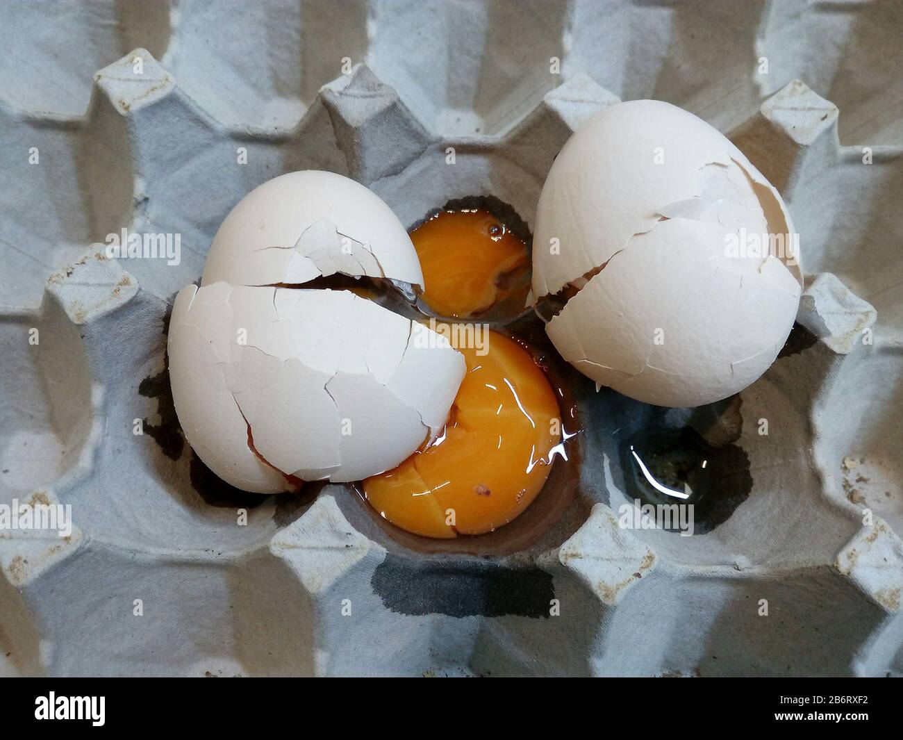 Coquilles d'aubergines et jaune d'œuf cassées brutes sur une boîte en carton blanc Banque D'Images