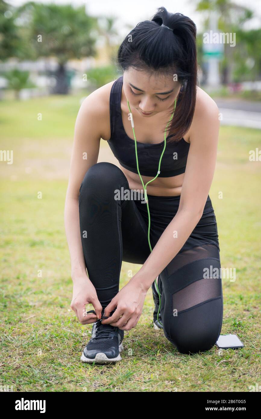 Woman runner tighting chaussures de course avant de tourner pendant l'exercice dans la soirée. Woman runner contrôle choes afin de se préparer à exécuter. Banque D'Images