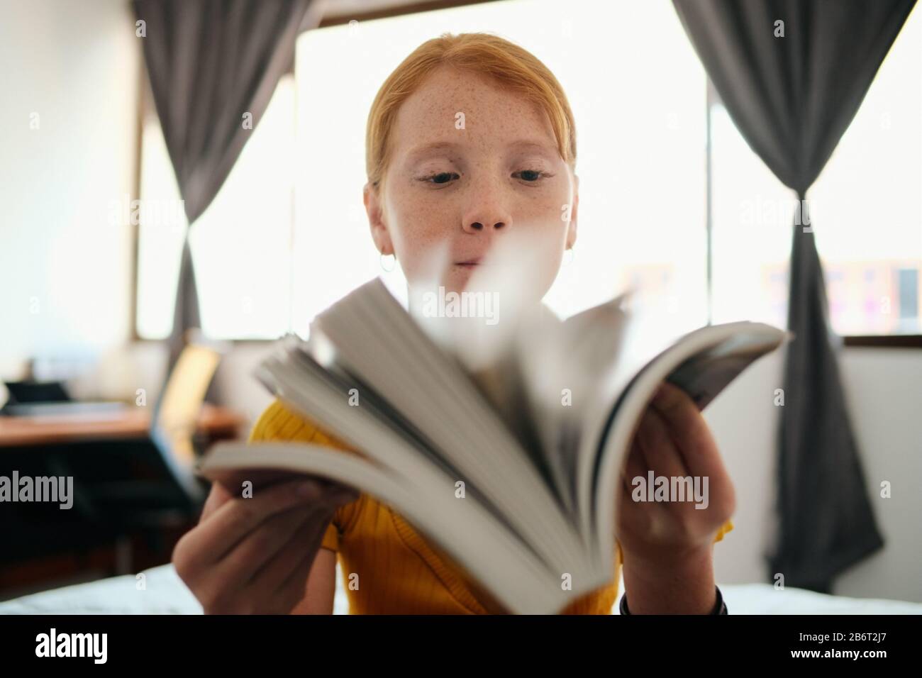 Jeune Fille Redhead Étudier Et Regarder Par Le Livre Banque D'Images