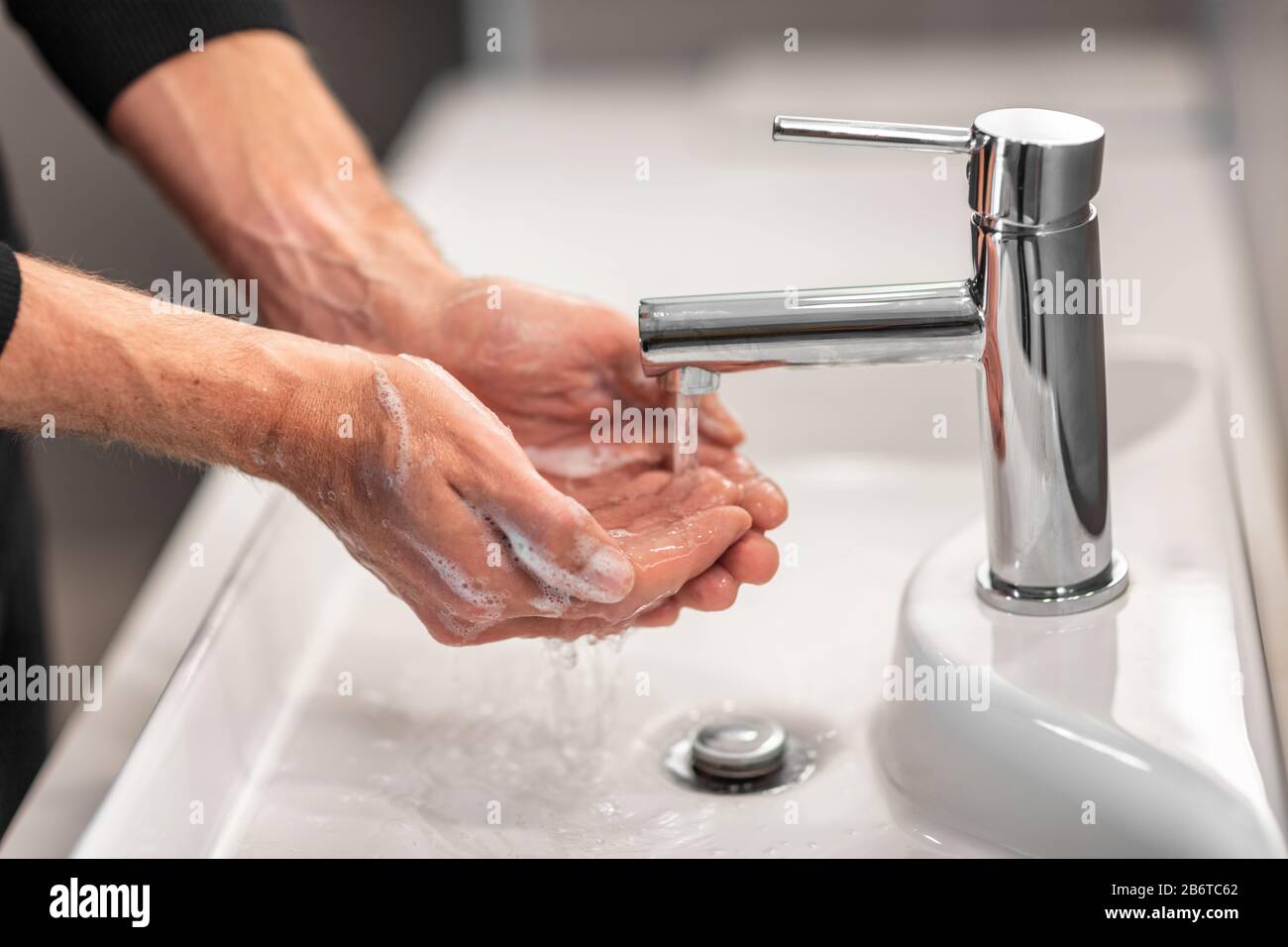 Laver les mains homme rincer le savon avec de l'eau courante à l'évier, Coronavirus prévention hygiène des mains. Protection contre la pandémie du virus Corona en nettoyant fréquemment les mains. Banque D'Images