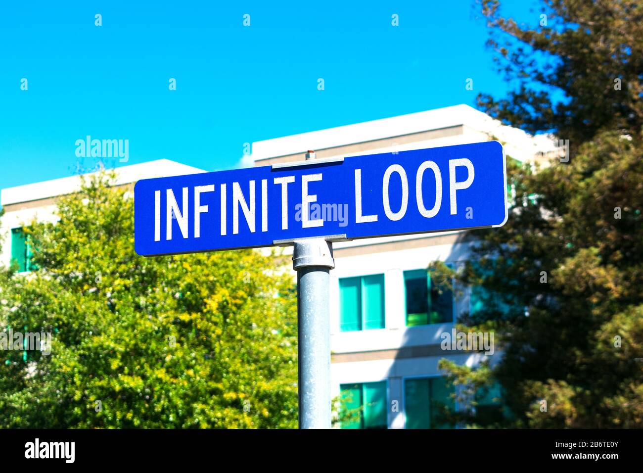 Le panneau de rue Infiniti Loop dirige les visiteurs vers le campus Apple et le magasin Apple Store situé au 1 Infinite Loop. Bâtiment de bureau de fond et arbres verts - Cu Banque D'Images