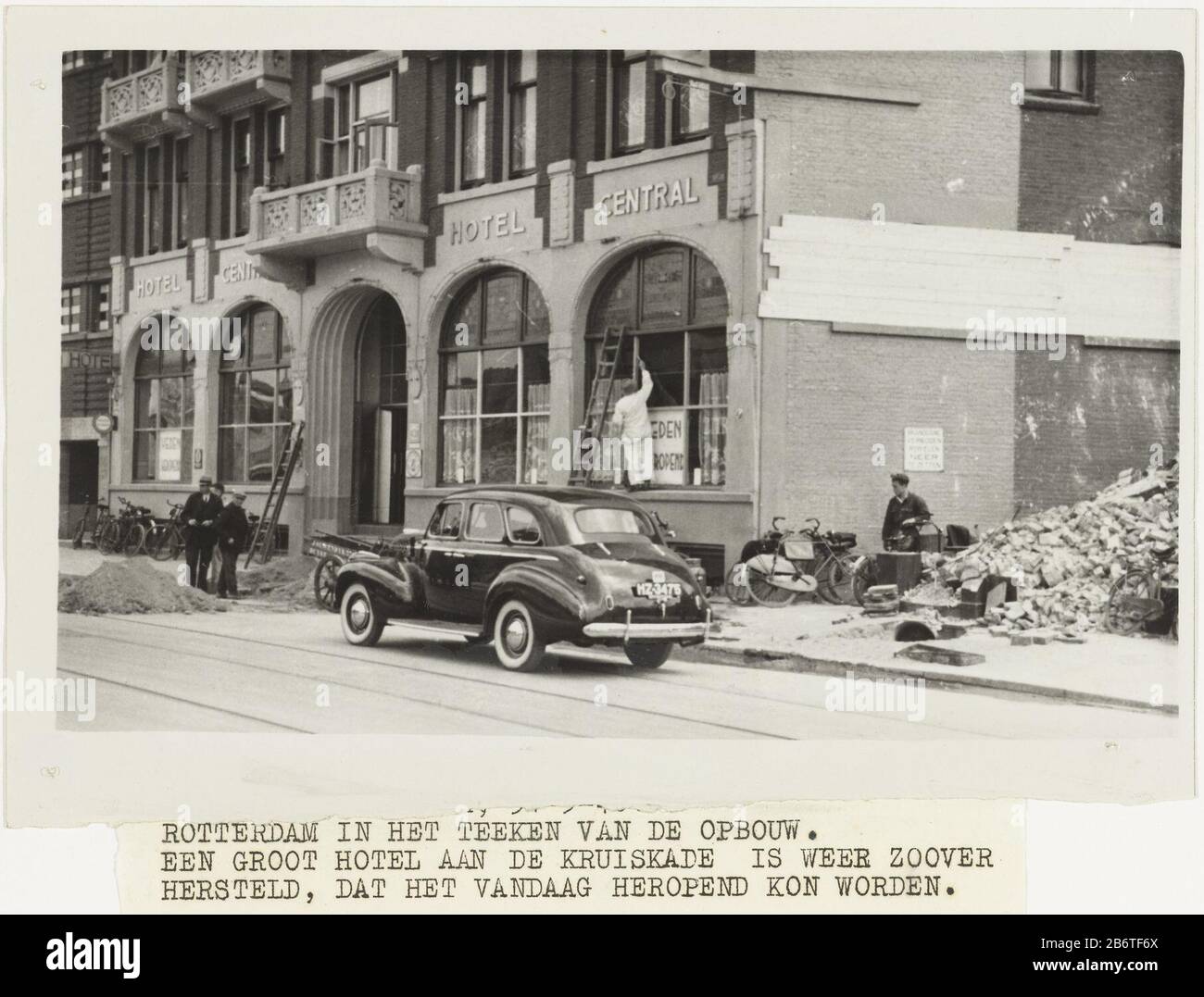 L'hôtel Heropen na het bombardant Hotel Central est légèrement affecté lors du bombardement de Rotterdam le 14 mai et ouvre de nouveau quelques semaines plus tard ses portes. Un peintre est occupé avec des travaux de restauration. Bandes de texte de photo geplakt. Fabricant : Photographe: Polygon Place fabricación: Rotterdam Date: 31 mai 1940 matériel: Technique du papier: Fotografie Sujet: Bombardement de la seconde Guerre mondiale de Rotterdam Quand: 1940 - 1940 Banque D'Images