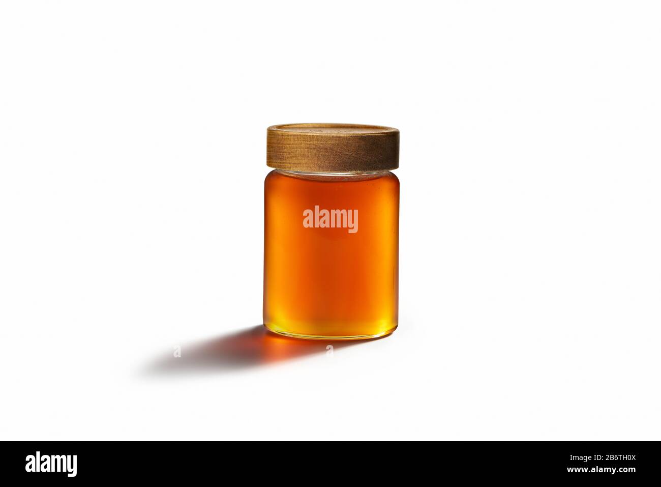 Miel frais avec couvercle en bois sur un récipient en verre. Suit la loi dominante centrale sur fond de livre blanc. Banque D'Images