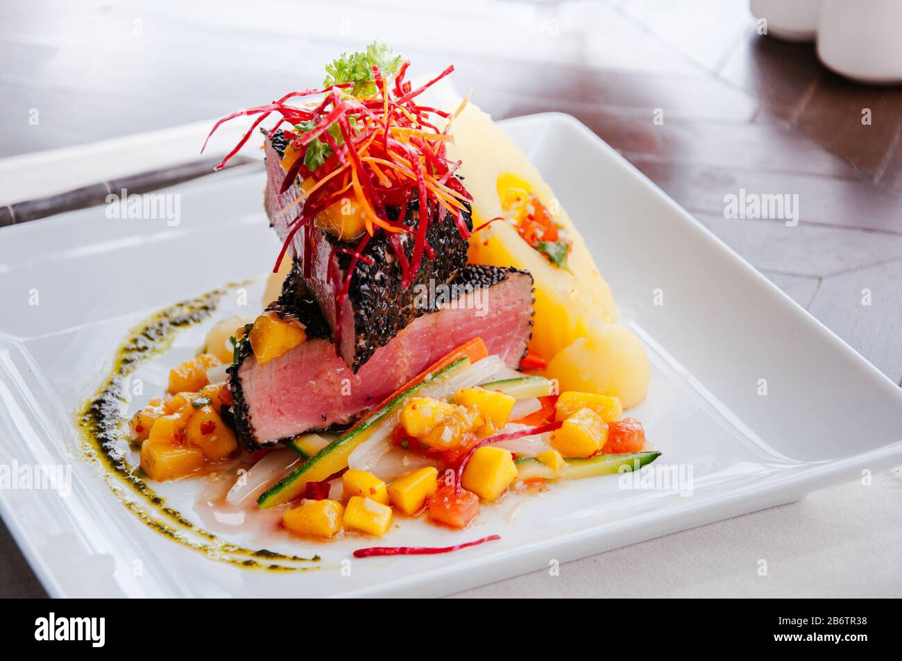 Ahi Tuna Cajun poêlé avec croûte de sésame, salade de salsa à la mangue aigre-douce et pommes de terre cuites sur une plaque blanche Banque D'Images